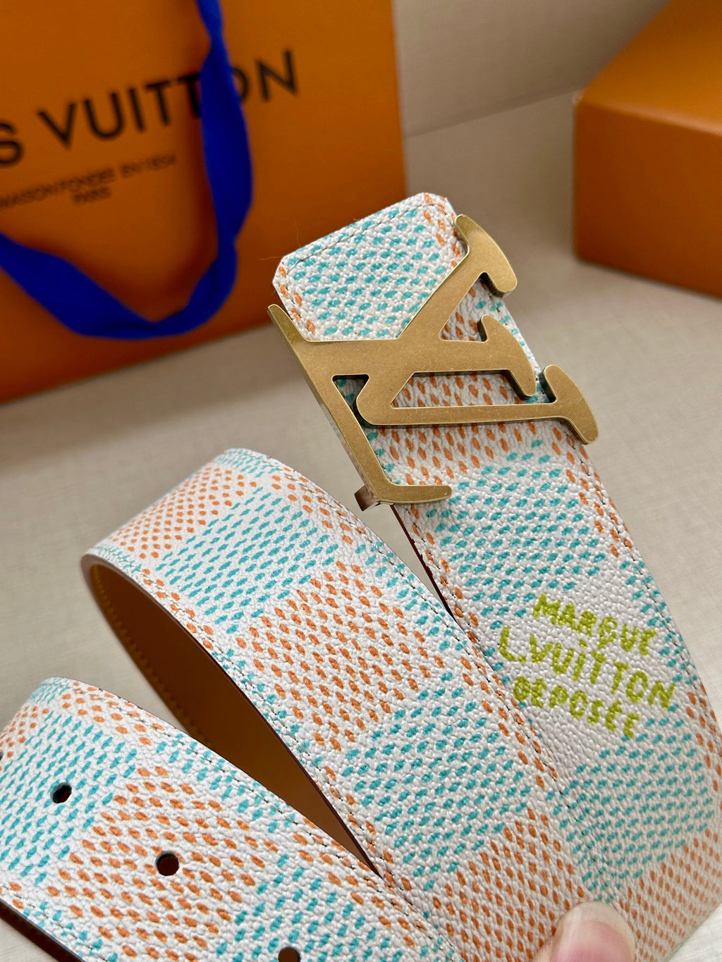 Patterned canvas belt with gold-tone buckle, light blue woven strap with hole row