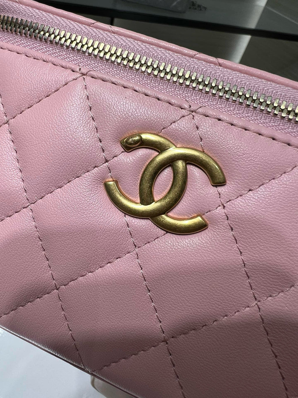 Pink quilted Chanel bag close-up with gold CC logo on the front