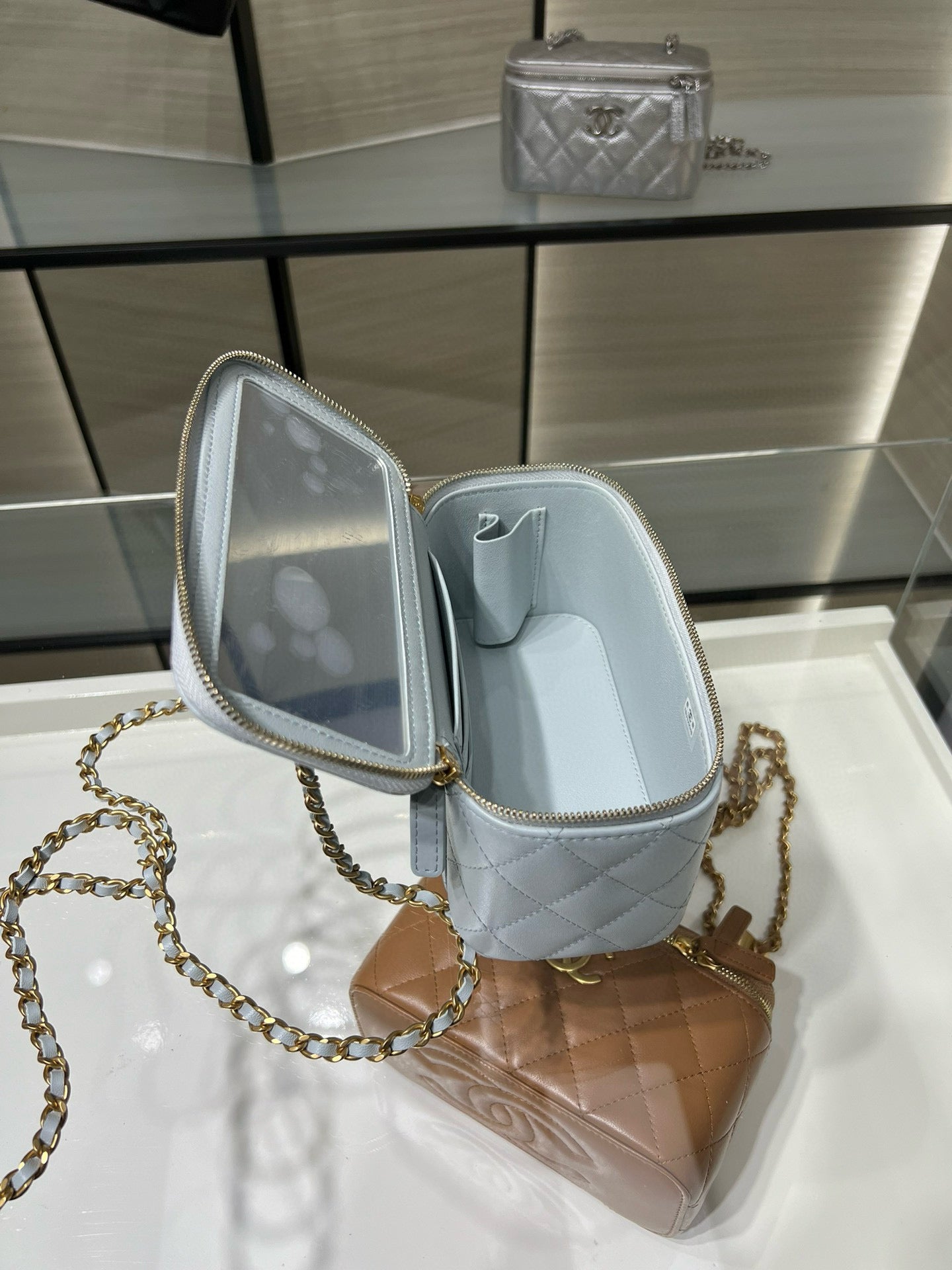 Light blue Chanel bag interior with open top and zip pocket, gold chain strap