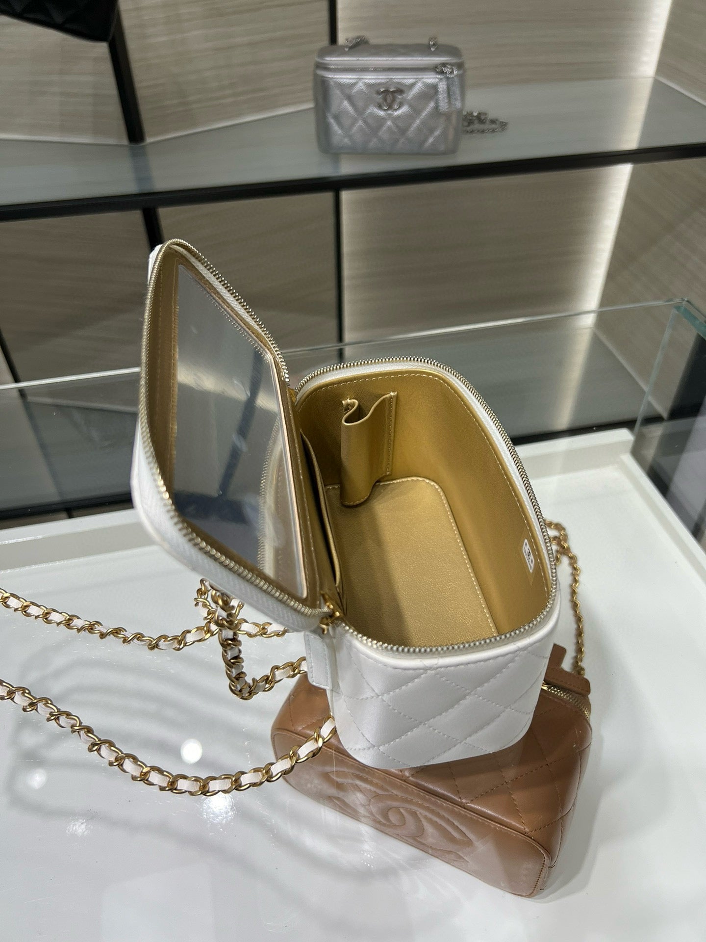 White quilted mini bag open at the top with gold-tone interior and chain strap