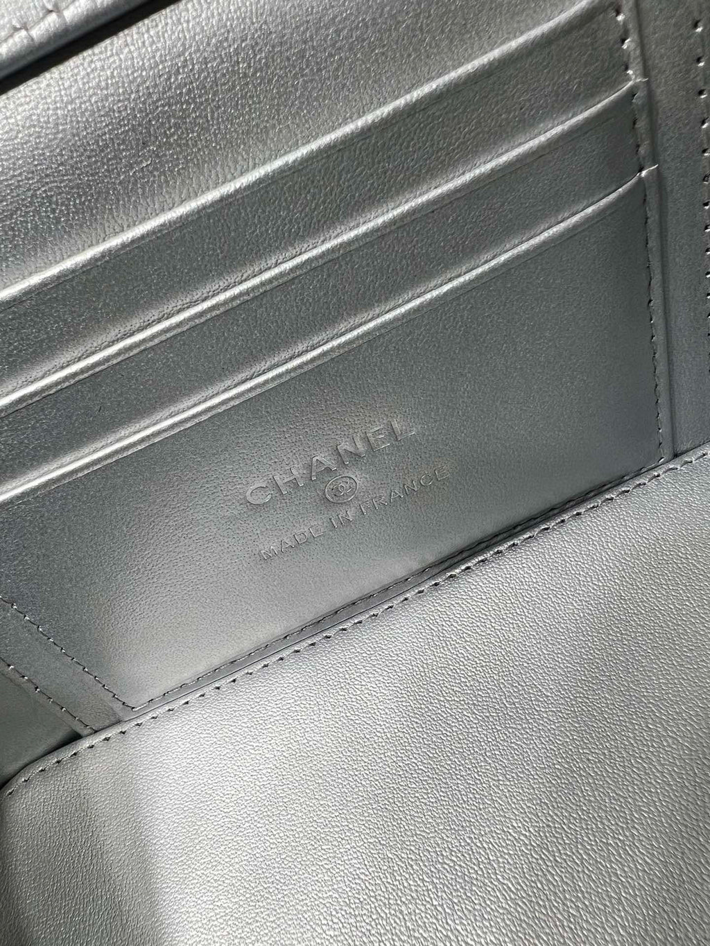 Chanel embossed on silver-tone leather flap with stitched edge and textured grain.