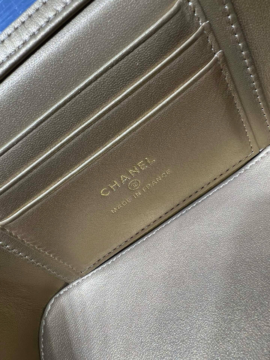 Chanel card slot detail on beige leather with stitched edges and CHANEL lettering