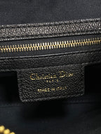 Black leather bag label with gold text and gold zipper trim detail