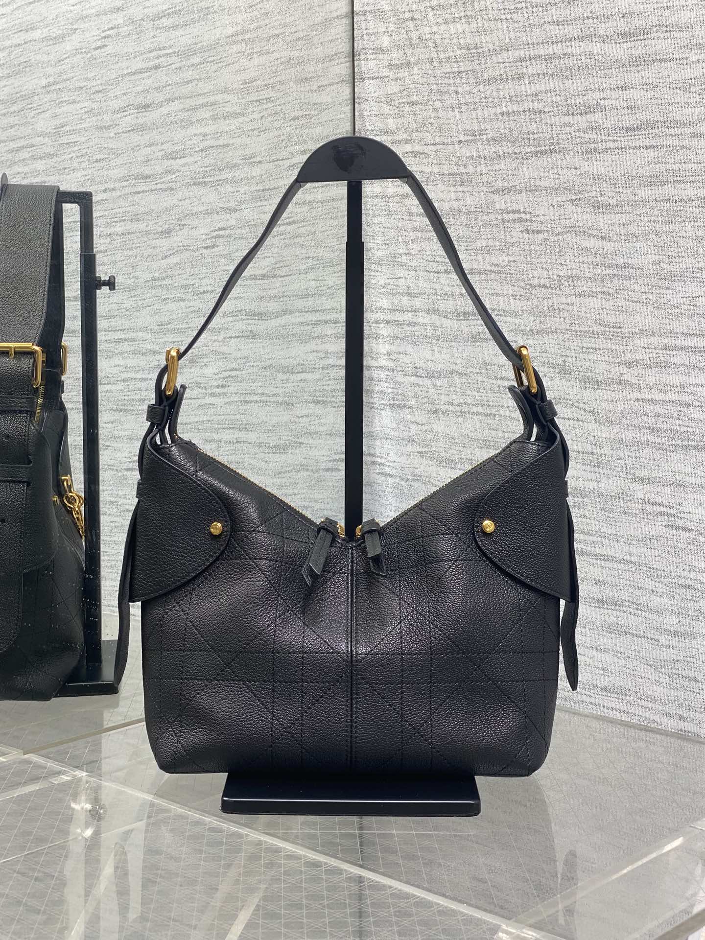 Black quilted hobo shoulder bag with top handles, snap detail, and gold hardware
