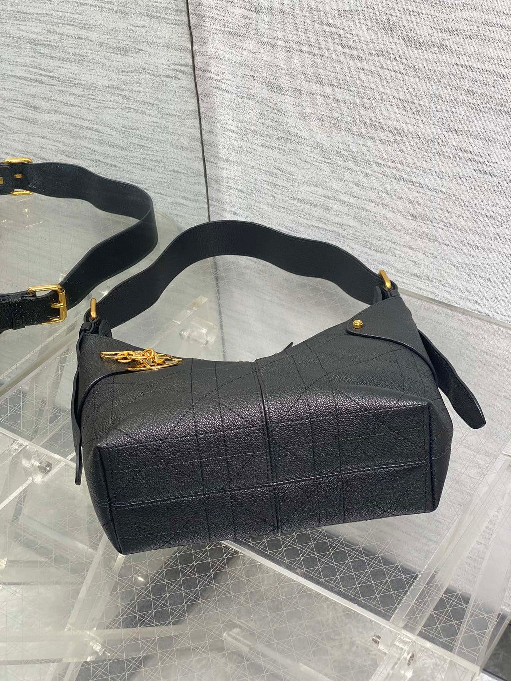 Black quilted hobo bag with wide top, curved handles, and side zipper pulls