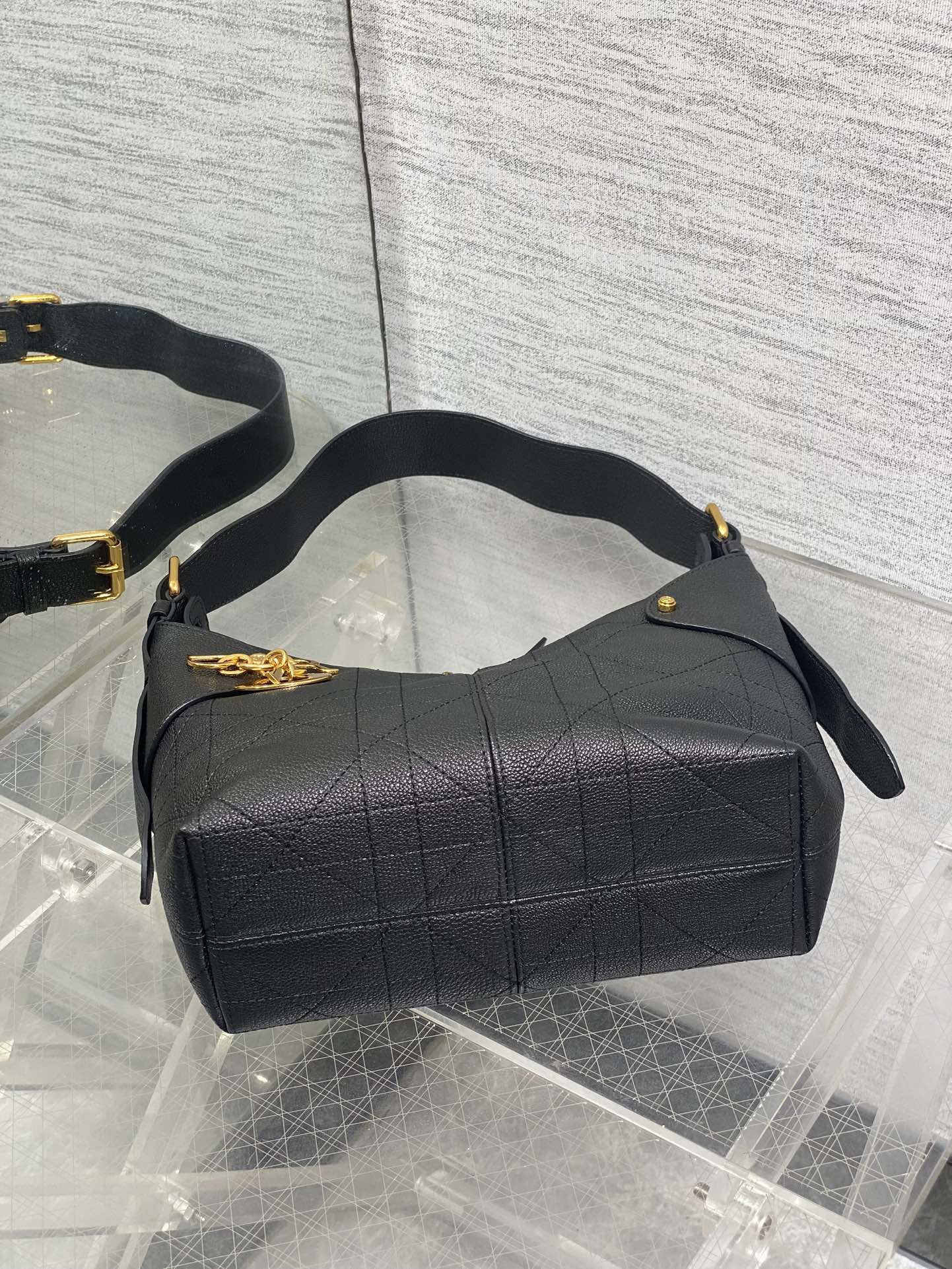 Black quilted hobo bag with wide top, curved handles, and side zipper pulls