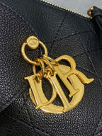 Close-up of gold-tone logo charm on black quilted leather bag