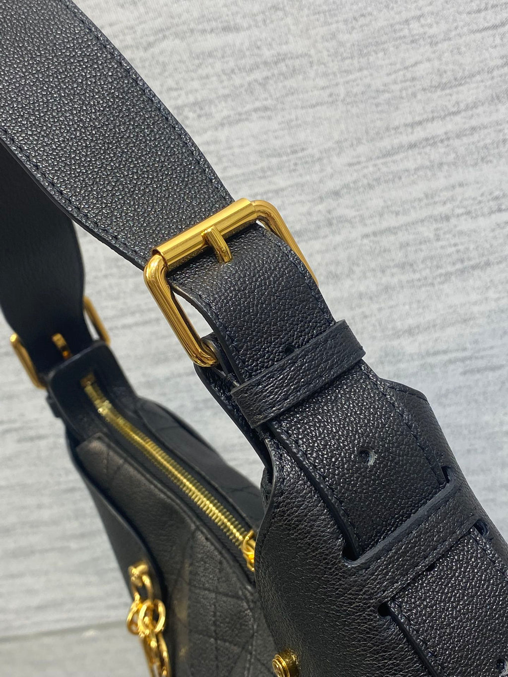 Black leather bag strap with gold buckle and matching zipper pull hardware
