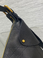 Black structured leather bag with curved top flap, gold zipper, and snap button