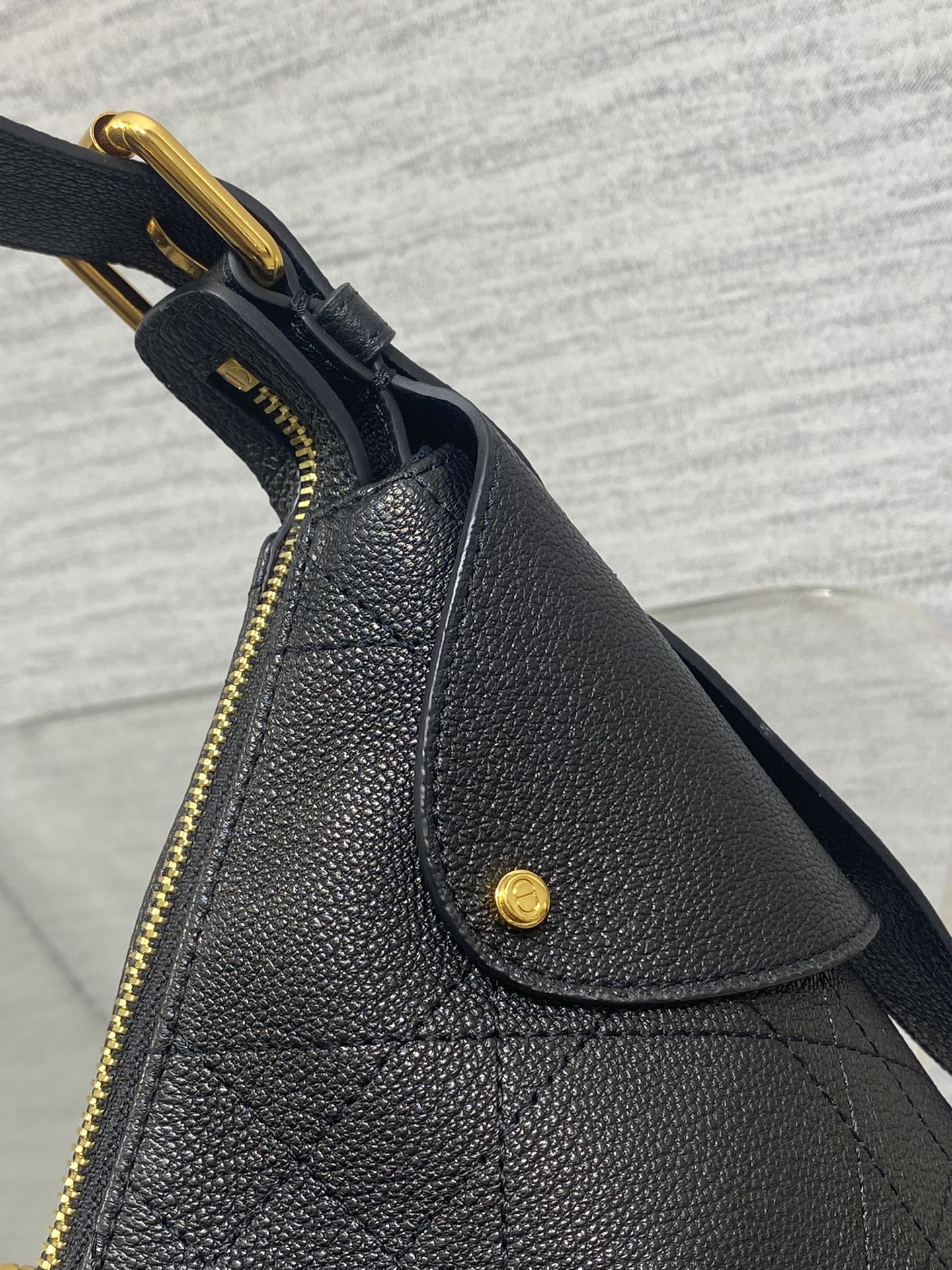 Black structured leather bag with curved top flap, gold zipper, and snap button