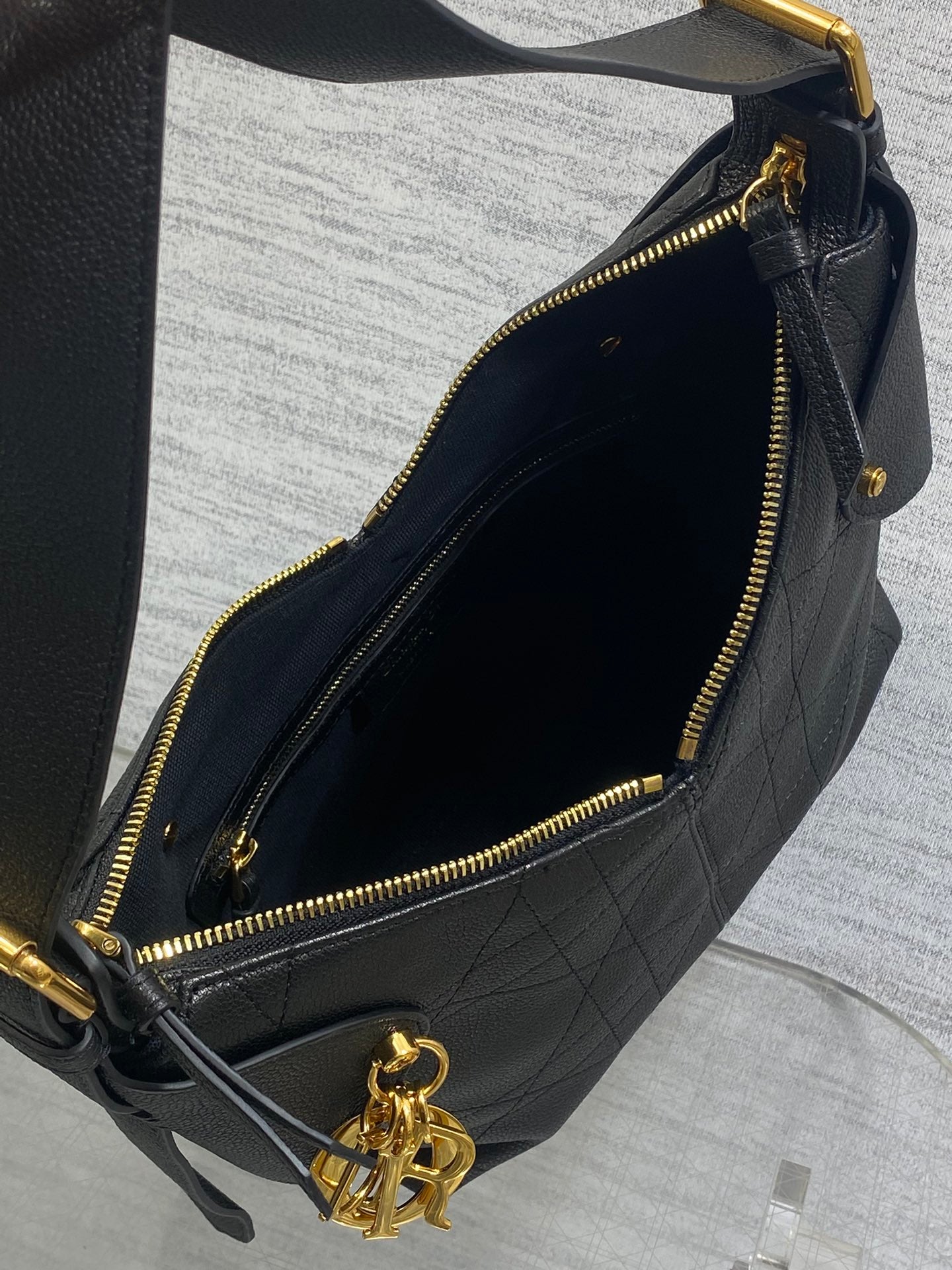 Black leather hobo bag open view with gold zipper and gold-tone logo charm