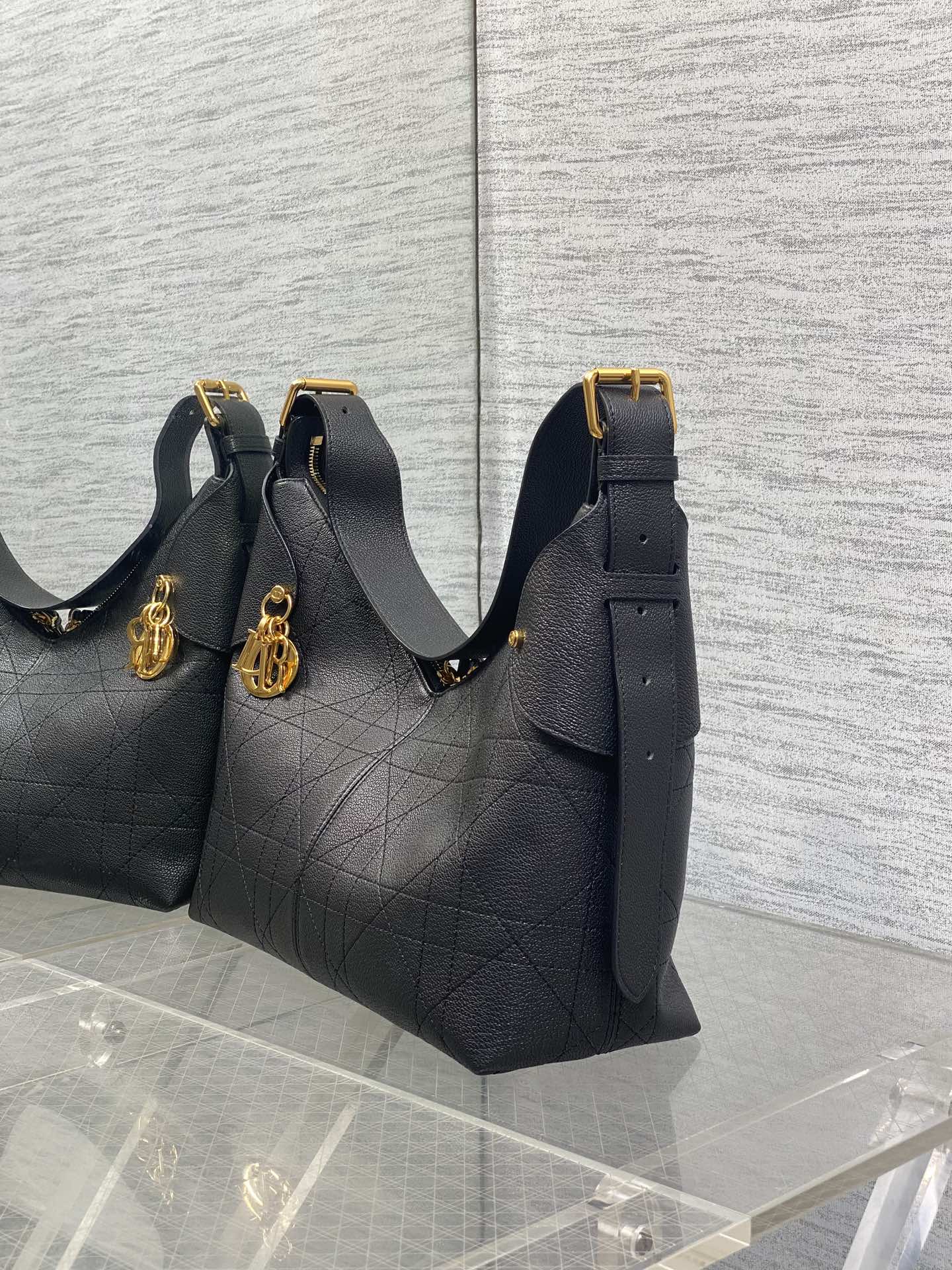 Dior quilted hobo bag with gold charm and shoulder straps, dark