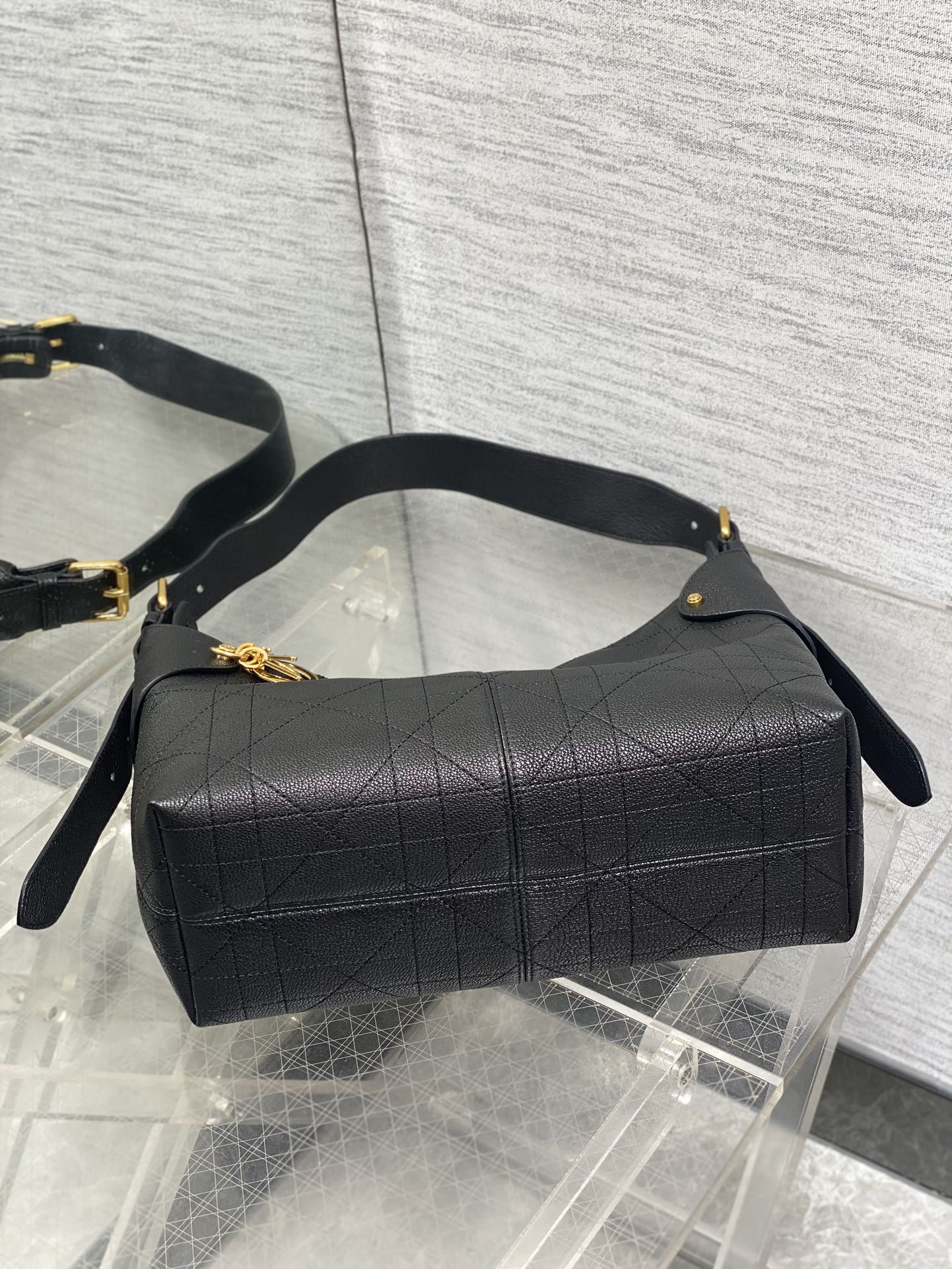 Dior quilted hobo bag with curved top handle and gold accents, dark