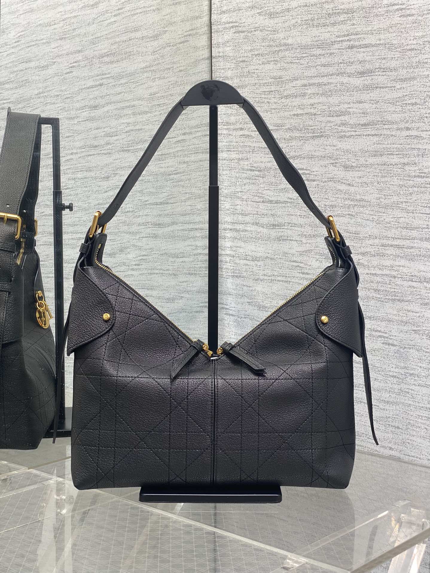 Dior quilted hobo bag with gold-tone hardware, angled shoulder straps, dark