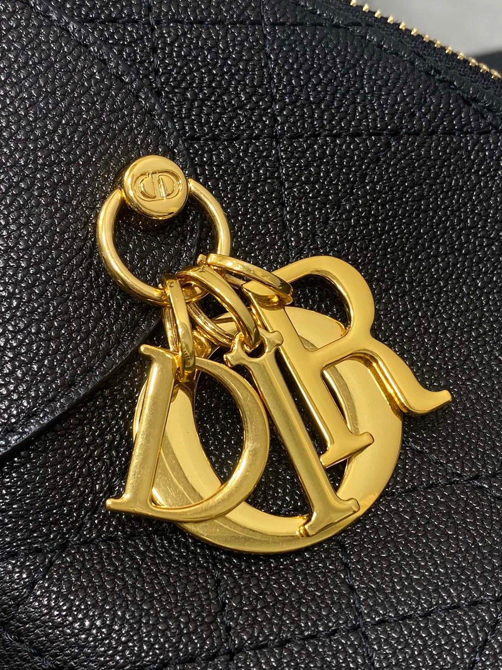 Dior gold-tone CD charm on dark quilted leather bag