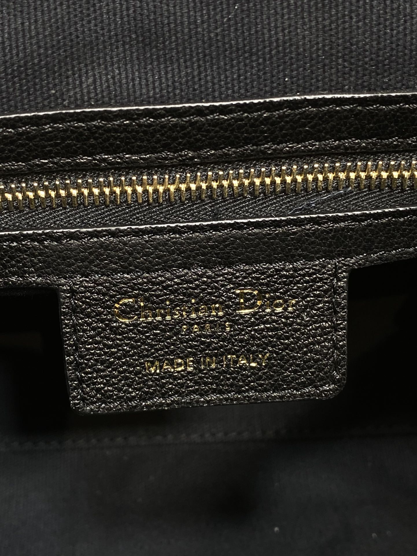 Dior bag label with gold text on dark leather