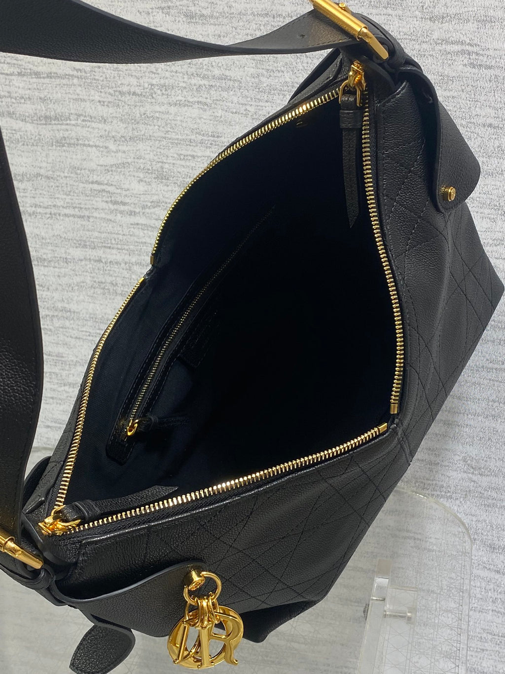 Dior hobo bag interior with dark lining and gold zipper closure, dark