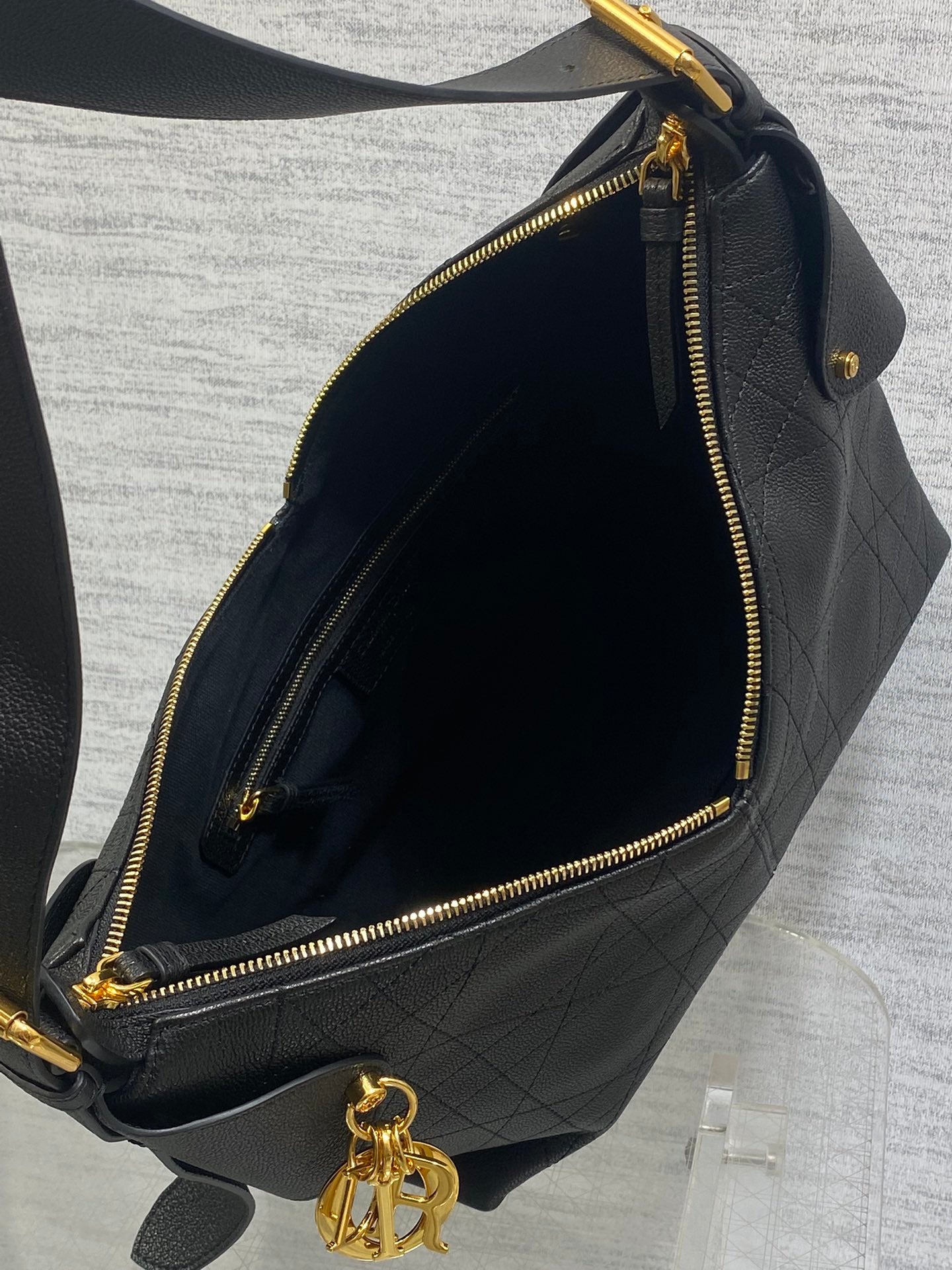 Dior hobo bag interior with dark lining and gold zipper closure, dark