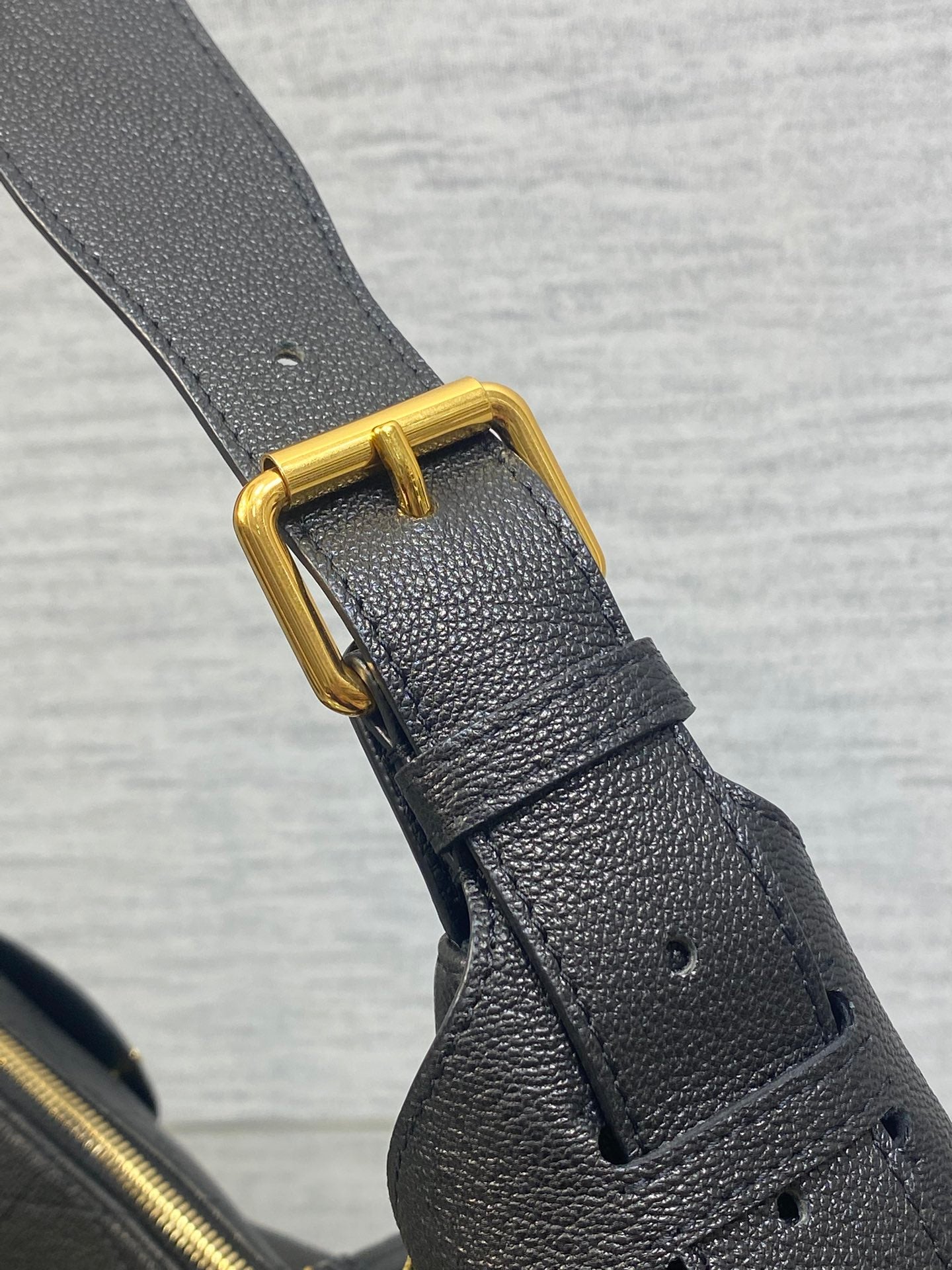 Dior leather shoulder strap with gold buckle and stitching on dark bag