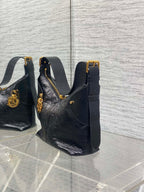 Black leather hobo bag with top handle, side strap, and gold buckle