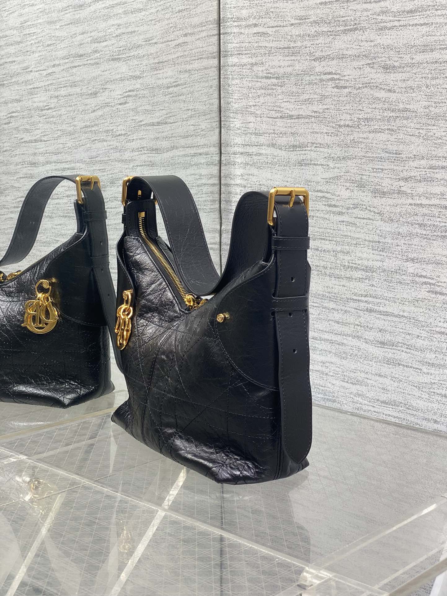 Black leather hobo bag with top handle, side strap, and gold buckle