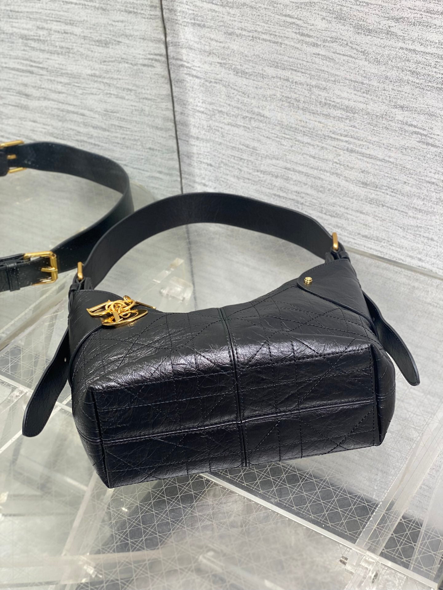 Black leather small hobo bag with gold emblem clasp and curved top handles