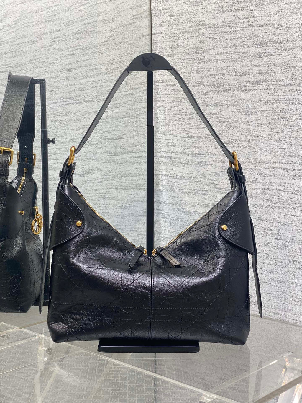 Black leather hobo bag with two shoulder straps and gold-tone hardware, side view
