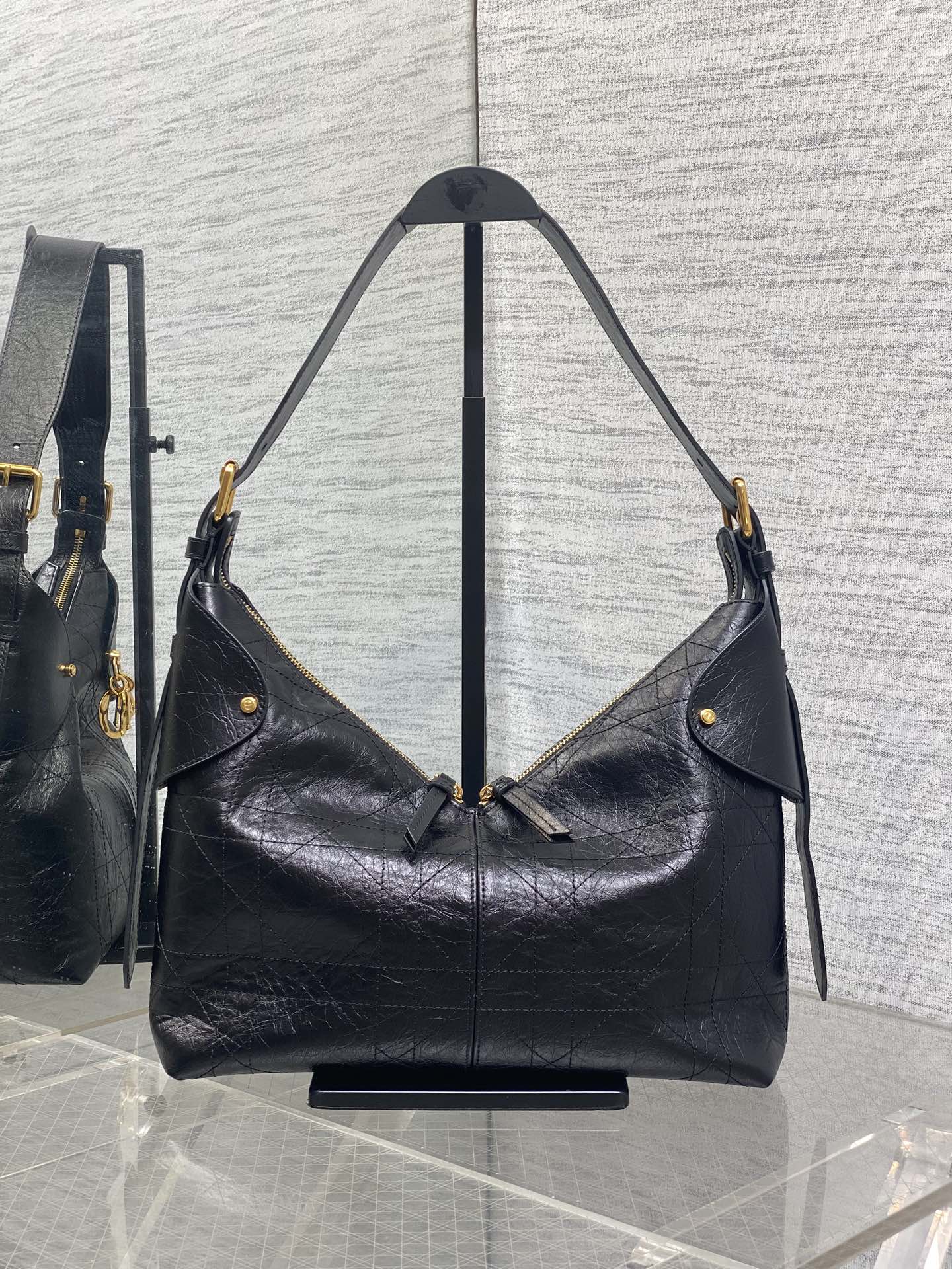 Black leather hobo bag with two shoulder straps and gold-tone hardware, side view