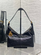 Black leather hobo bag with top handles and gold-tone hardware, front flap detail