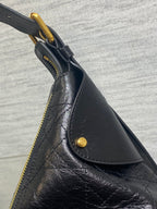 Black leather slouch bag with gold zipper and curved front seam detail