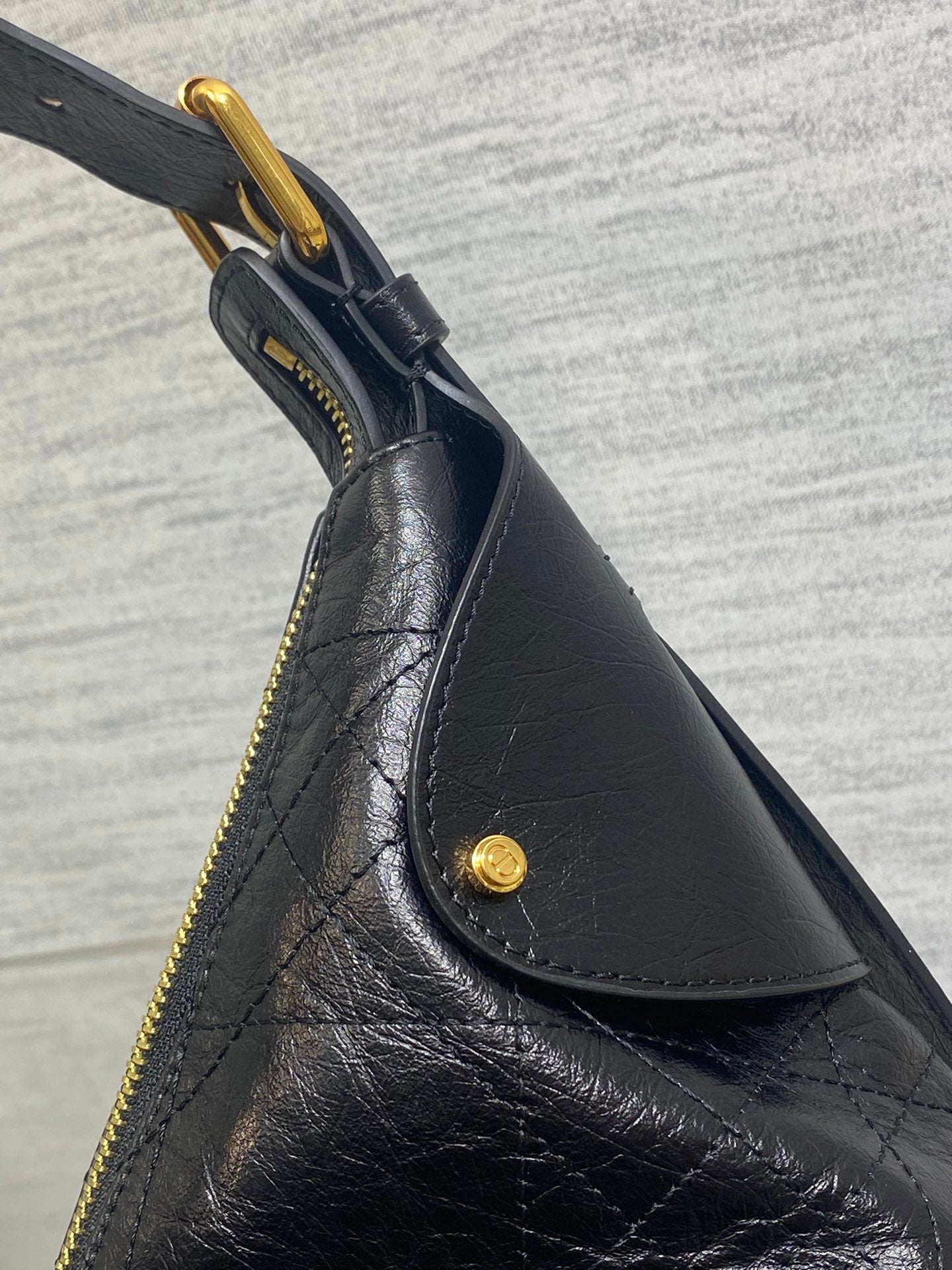 Black leather slouch bag with gold zipper and curved front seam detail