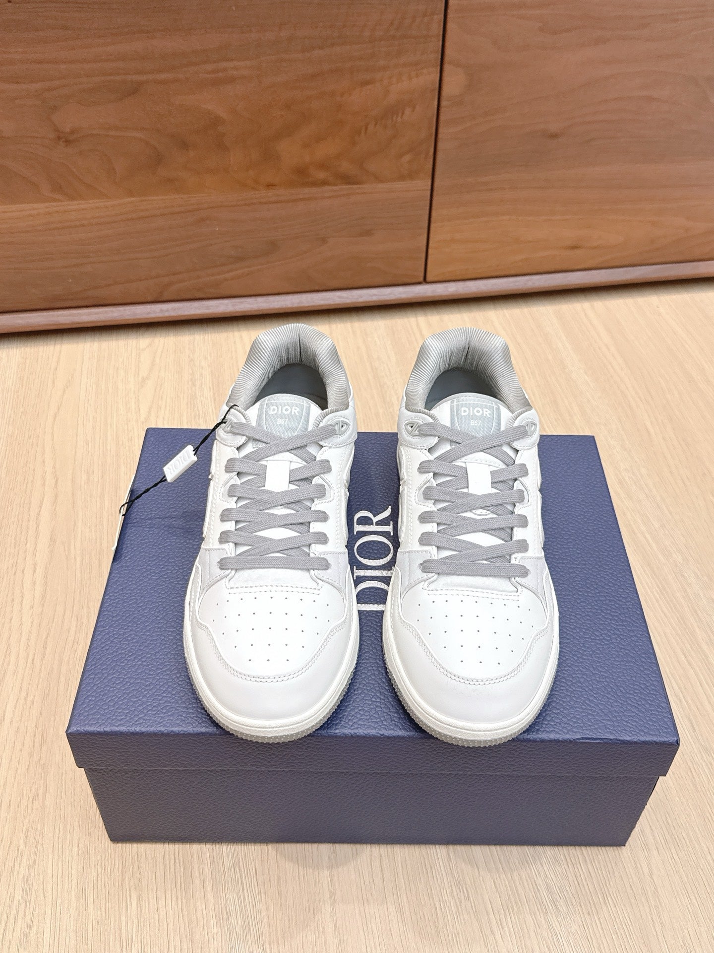 White Dior low-top sneakers with gray laces and side “DIOR” logo, on box