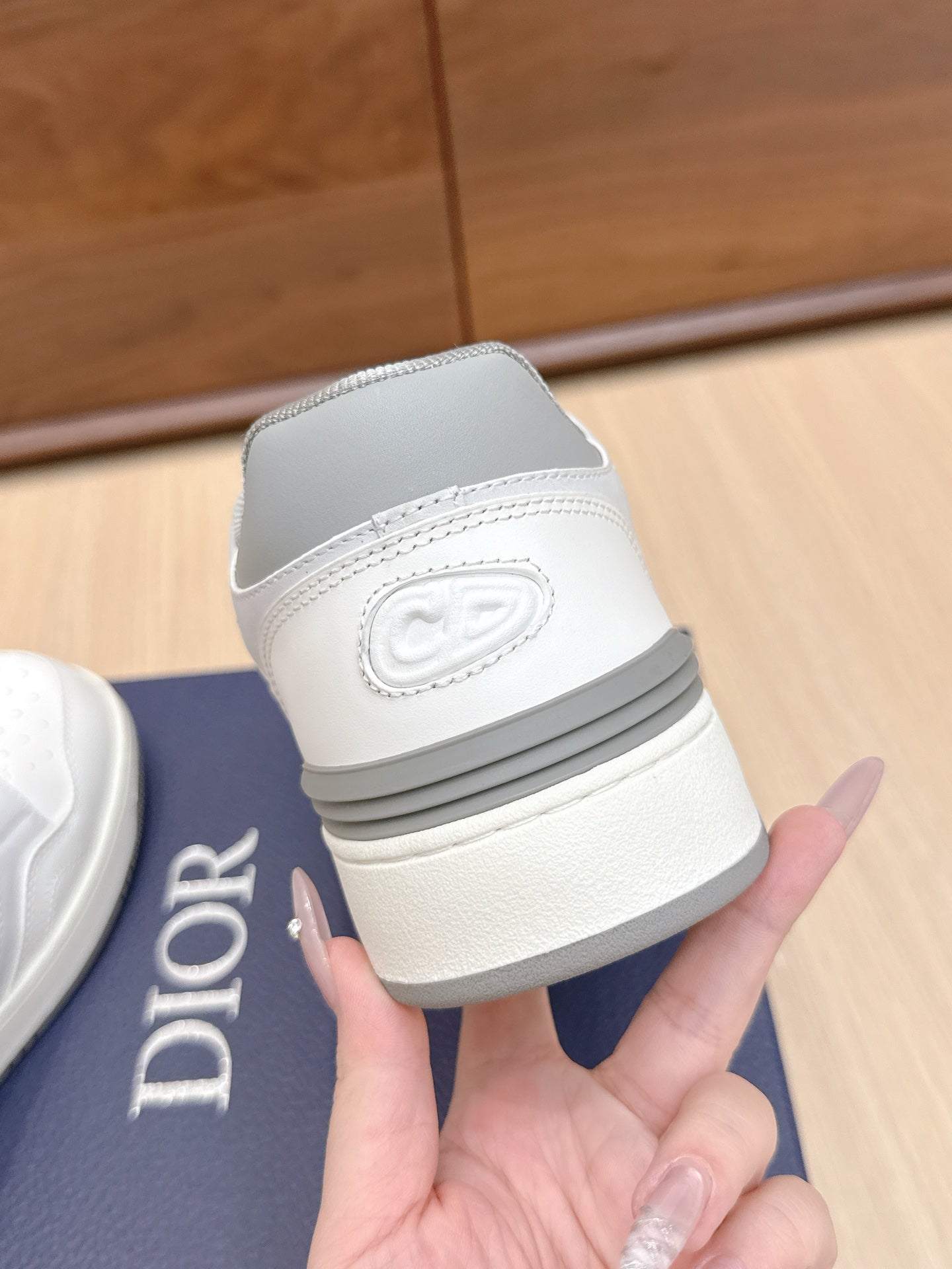 White Dior sneaker heel with embossed logo and padded collar, shown on box