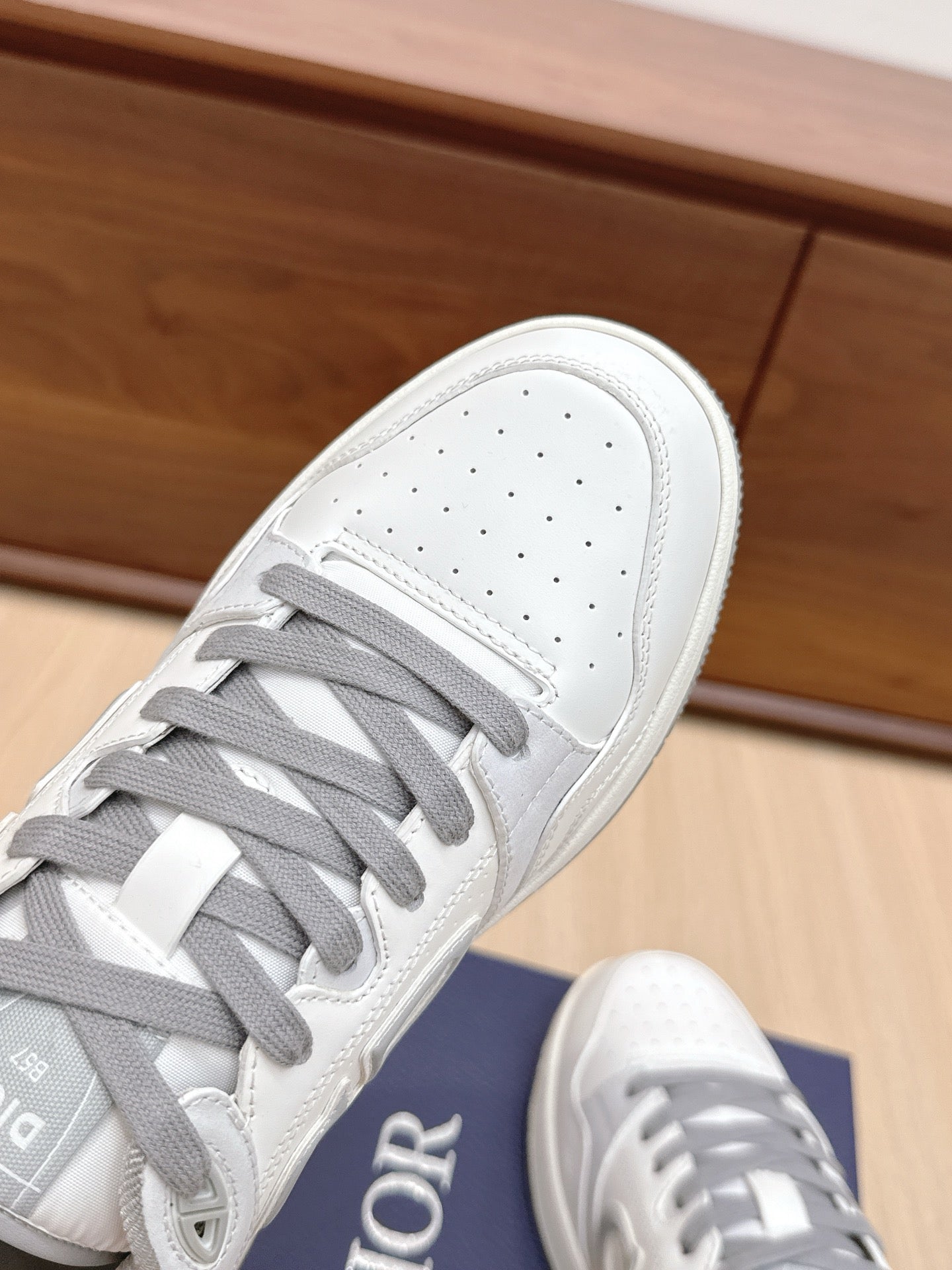 White Dior sneaker toe with perforations, gray laces, and white rubber sole edge