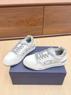 White Dior low-top sneakers with gray laces and side “DIOR” logo, on navy box