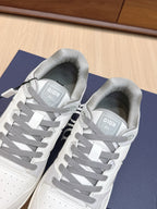 White Dior sneakers with gray laces and tongue labels, side view pair on box