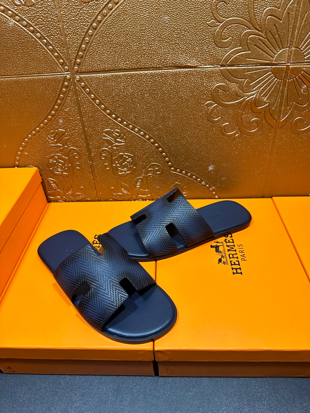 Pair of dark blue textured leather slide sandals with open toe and H cutouts