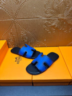 Hermes blue and black slide sandals, hand-held close-up of H cutout strap