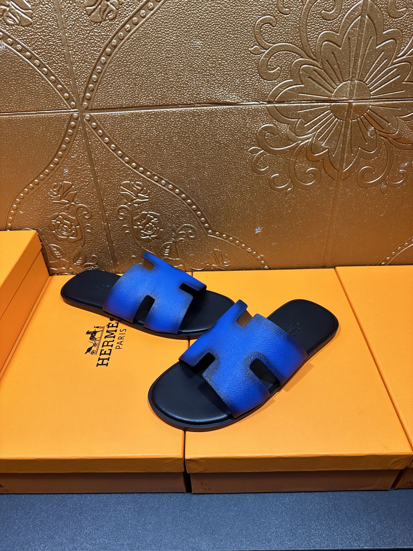 Hermes blue and black slide sandals, hand-held close-up of H cutout strap