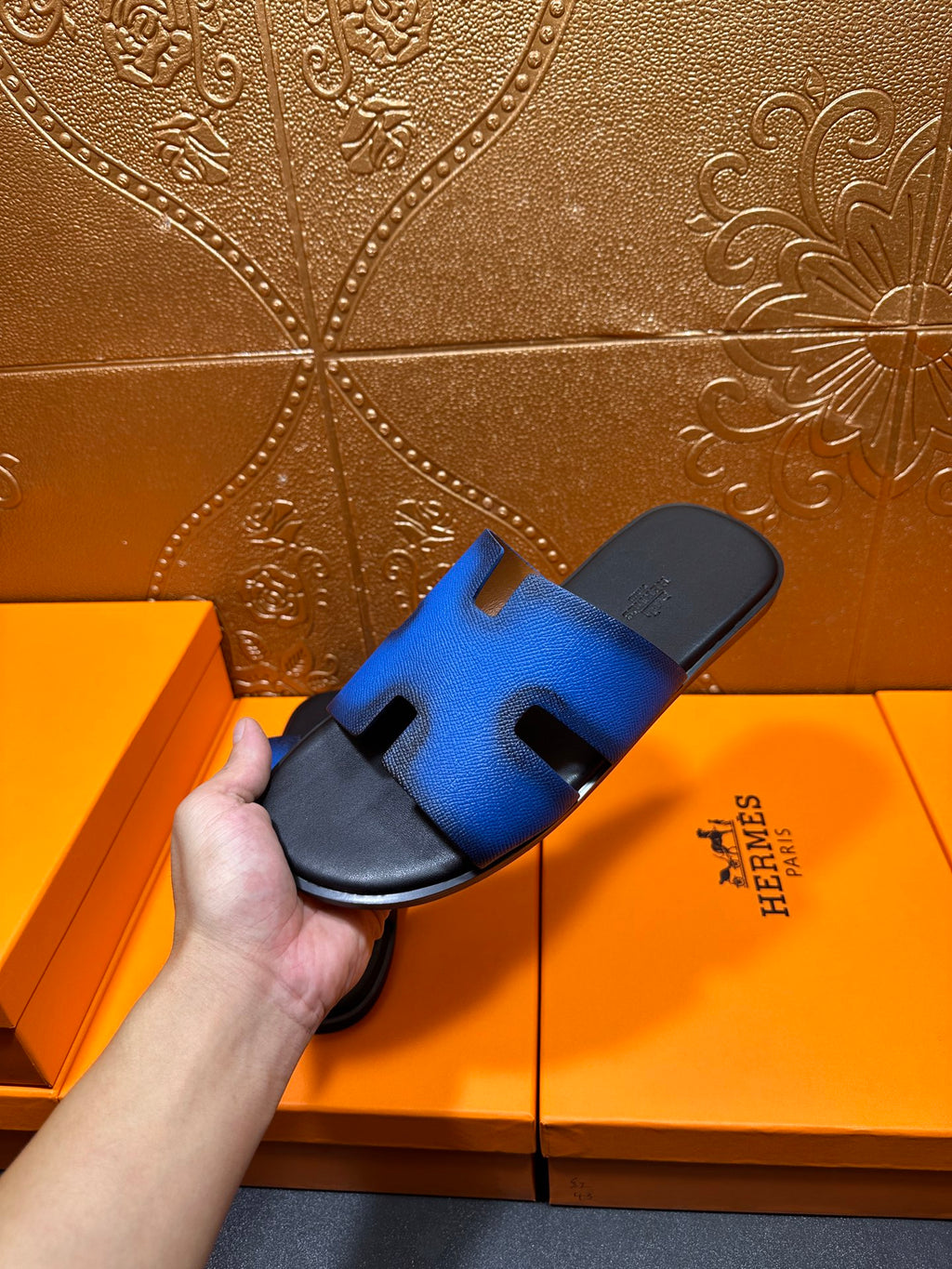 Hermes blue slide sandals with black footbed and H cutout strap, close-up
