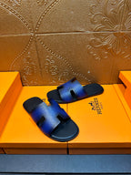Blue leather slide sandals with sculpted cutout strap and black rubber footbed