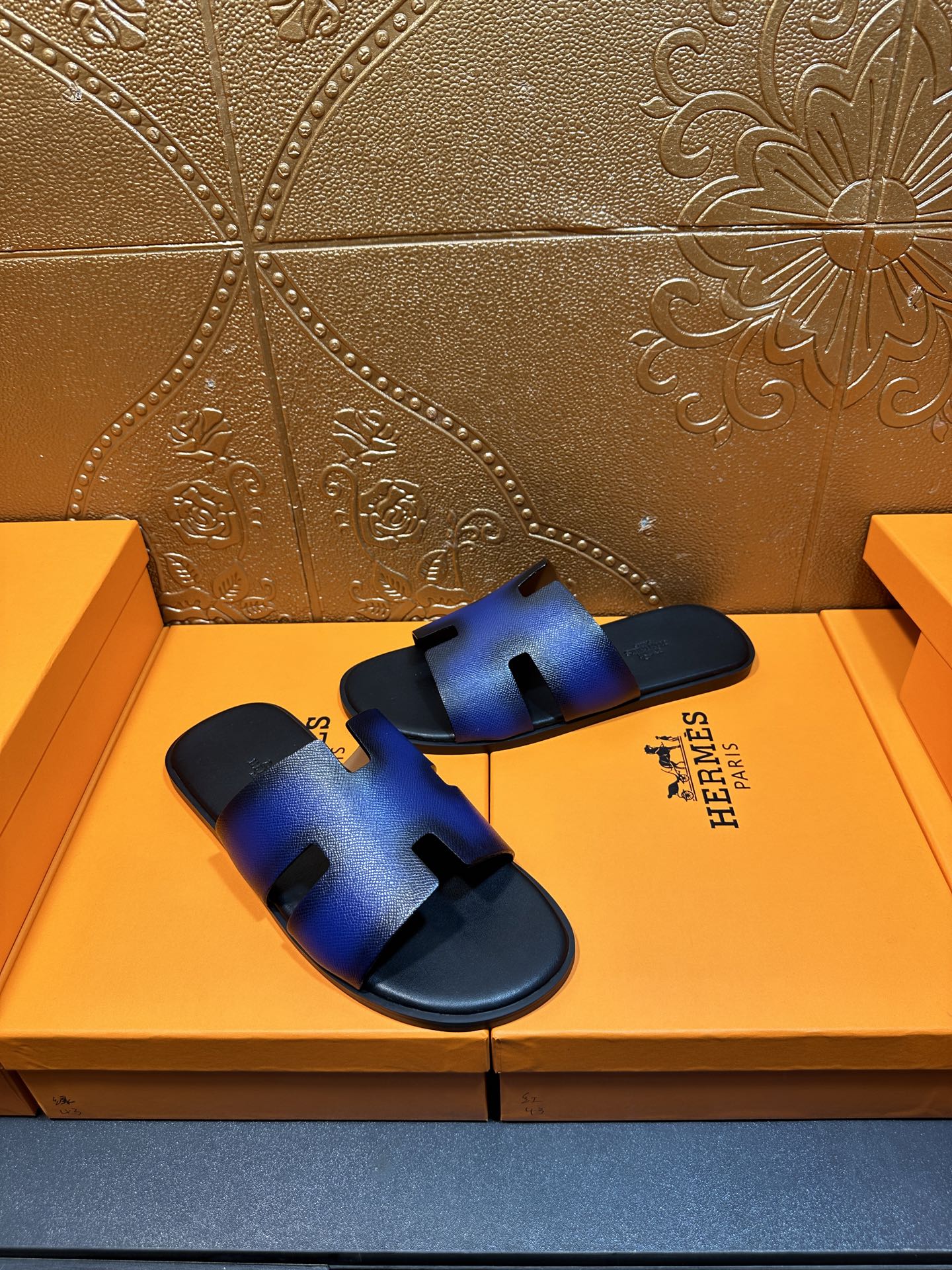 Blue leather slide sandals with sculpted cutout strap and black rubber footbed