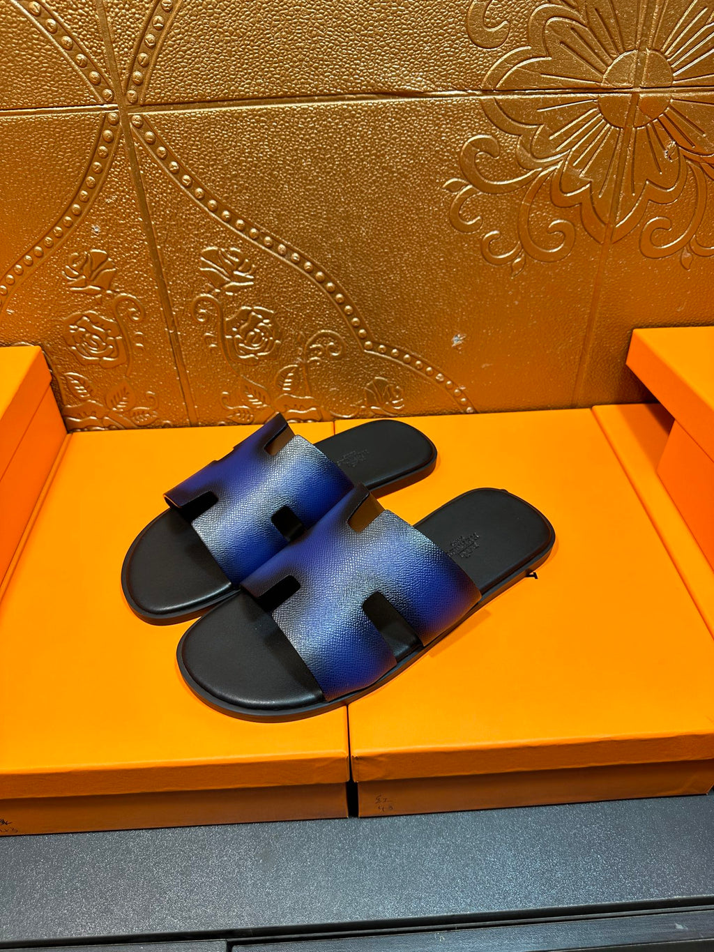 Pair of blue leather slide sandals with H-shaped cutout straps and black footbed