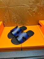 Pair of blue leather slide sandals with H-shaped cutout straps and black footbed