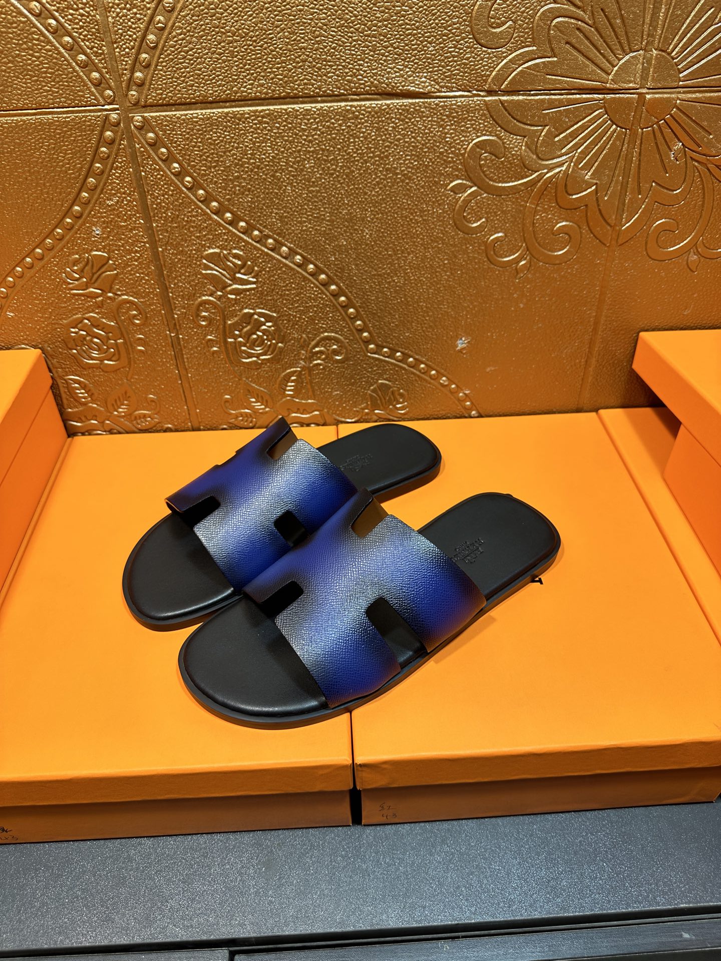 Pair of blue leather slide sandals with H-shaped cutout straps and black footbed