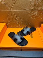 Dark blue leather slide sandals with wide HERMES logo strap and open toe.