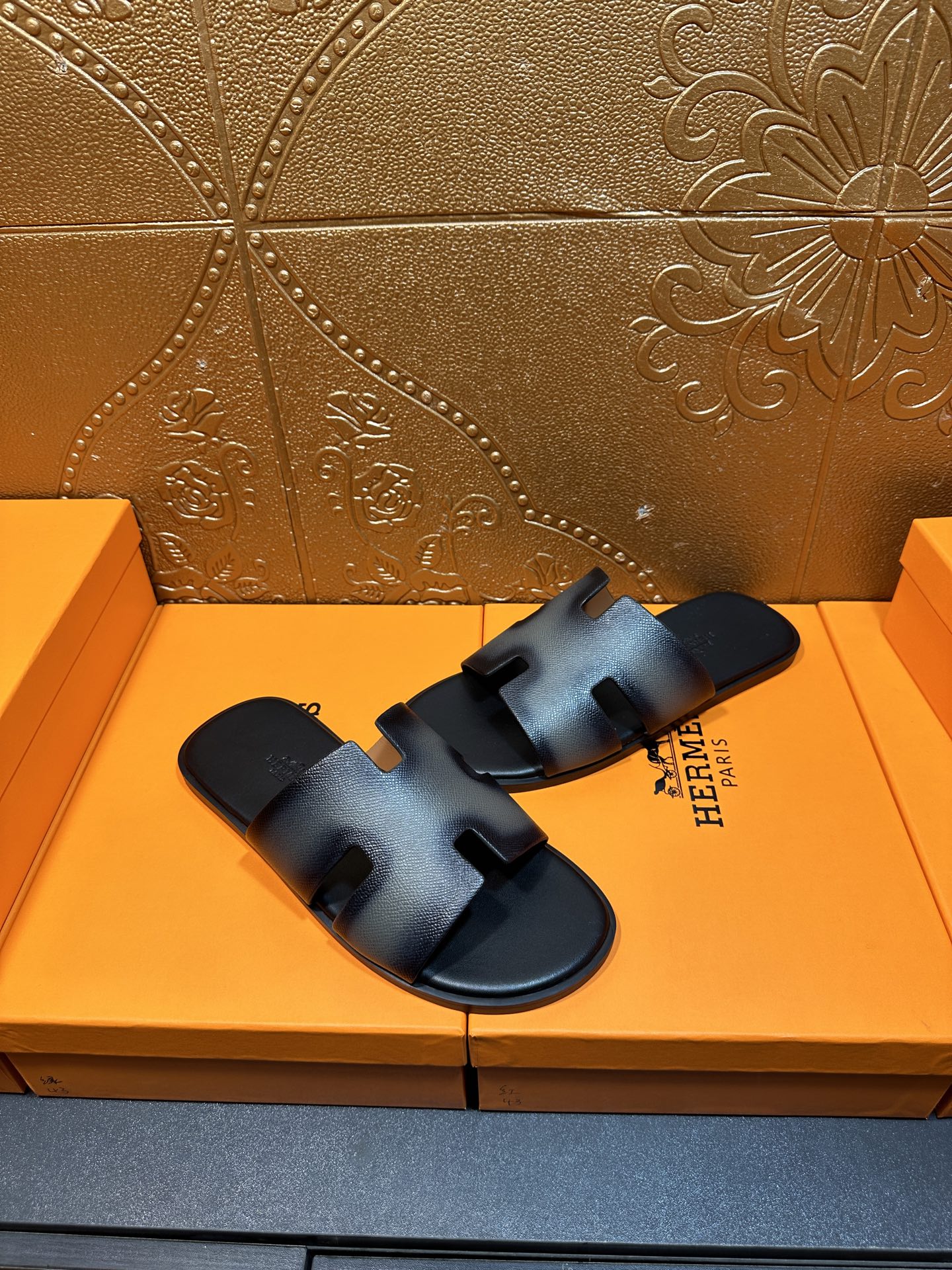 Dark blue leather slide sandals with wide HERMES logo strap and open toe.