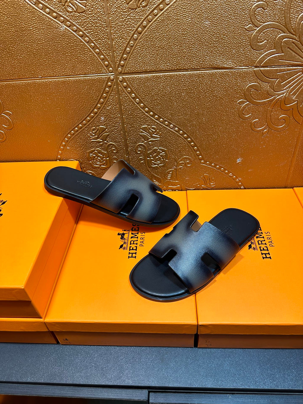 Two dark blue leather slide sandals with wide straps and cushioned footbed.