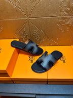 Two dark blue leather slide sandals with wide straps and cushioned footbed.