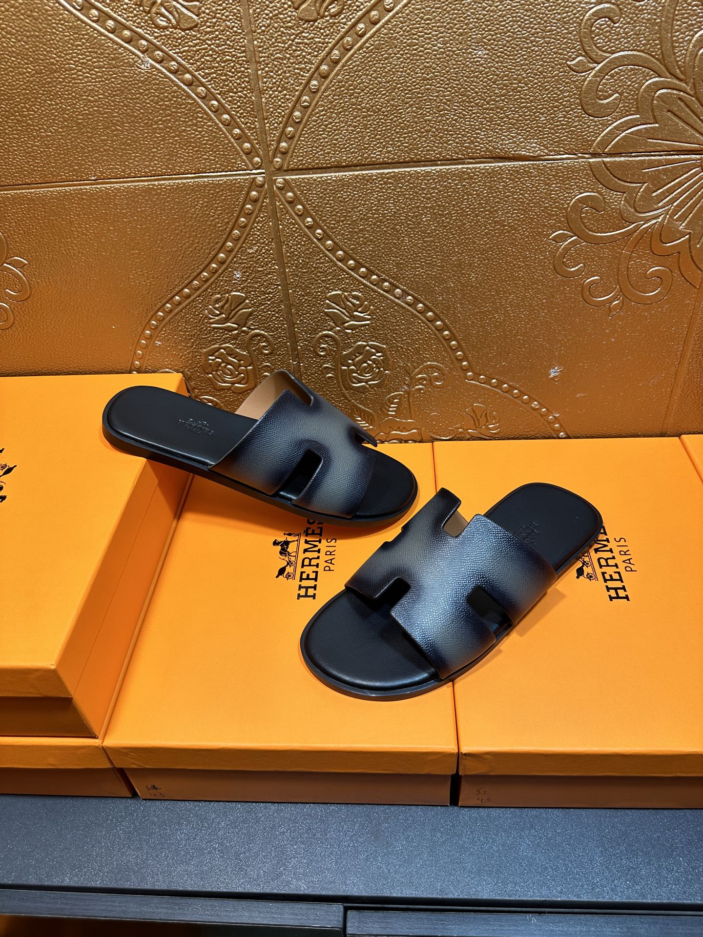 Two dark blue leather slide sandals with wide straps and cushioned footbed.